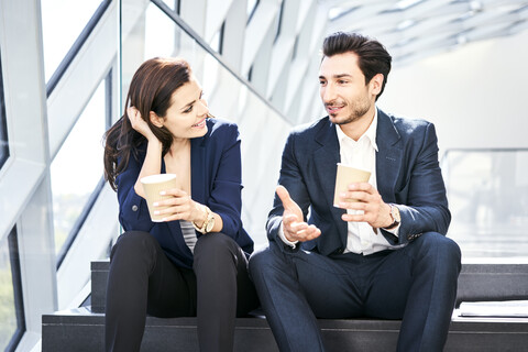 Lächelnde Geschäftsfrau und Geschäftsmann in einer Kaffeepause in einem modernen Büro, lizenzfreies Stockfoto
