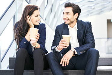 Smiling businesswoman and businessman having a coffee break in modern office - BSZF00551