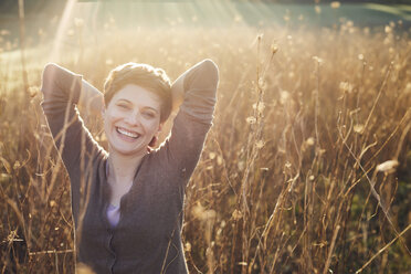 Porträt einer lachenden Frau, die sich in der Natur entspannt - PNEF00644