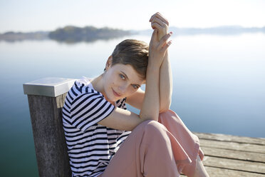 Portrait of woman sitting on jetty at lake - PNEF00647