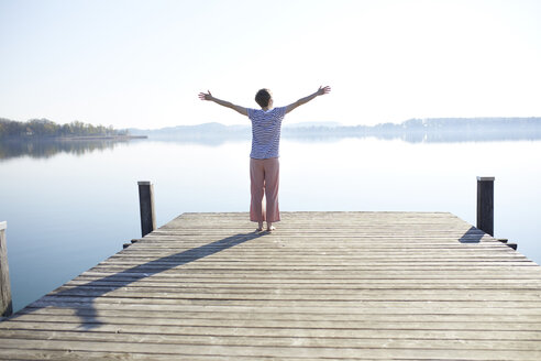 Germany, Bavaria, back view of woman standing on jetty at lake - PNEF00655