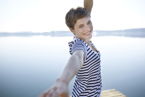 Germany, Bavaria, portrait of happy woman standing in front of lake stock photo
