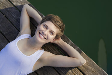 Portrait of smiling woman lying on jetty - PNEF00660