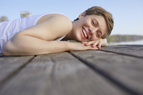 Porträt einer lachenden Frau, die auf einem Steg liegt, lizenzfreies Stockfoto