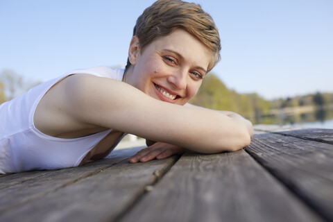 Porträt einer glücklichen Frau auf dem Steg liegend, lizenzfreies Stockfoto
