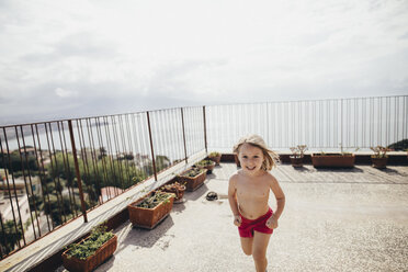Italien, Neapel, glückliches kleines Mädchen läuft auf Dachterrasse - KMKF00247