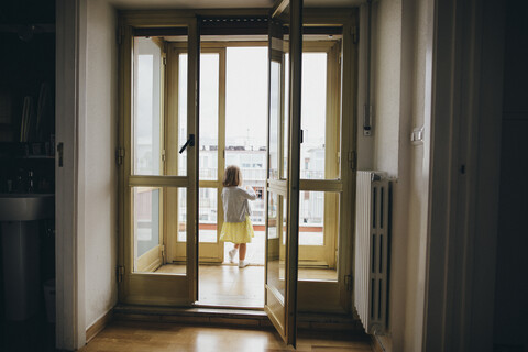 Italy, Naples, back view of little girl standing at door of roof terrace stock photo