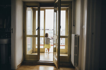 Italy, Naples, back view of little girl standing at door of roof terrace - KMKF00249
