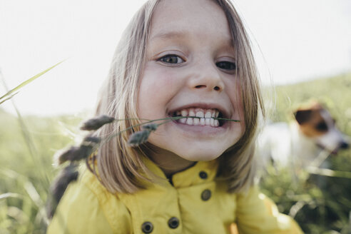 Portrait of little girl on a meadow holding blade of grass with her teeth - KMKF00261