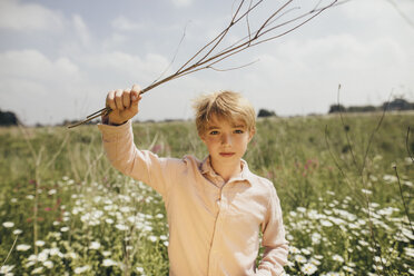 Porträt eines blonden Jungen mit Zweigen in der Natur - KMKF00264