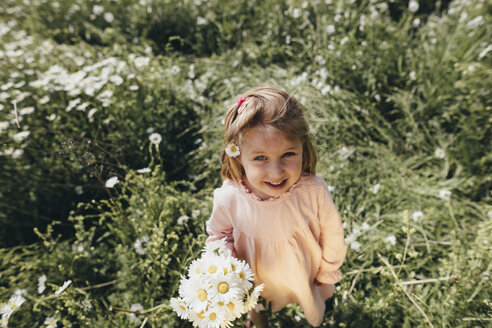 Porträt eines kleinen Mädchens mit gepflücktem Blumenstrauß auf einer Wiese - KMKF00269