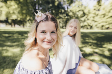 Porträt von zwei lächelnden jungen Frauen, die sich in einem Park entspannen - KMKF00272