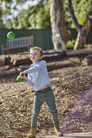 Junge im Garten spielt mit Schaumstoff-Baseballschläger und Ball, lizenzfreies Stockfoto