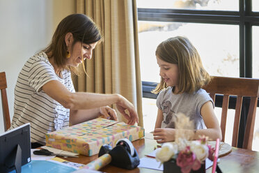 Mutter und Tochter verpacken Geschenk am Tisch zu Hause - BEF00165