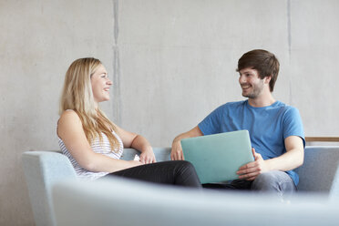 Junge männliche und weibliche Studenten sitzen auf einem Sofa mit Laptop an einer Hochschule - CUF22163