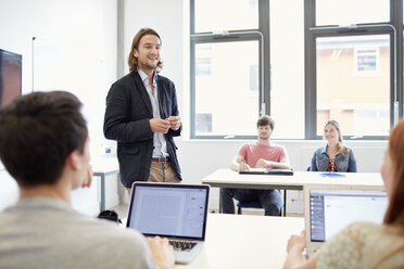 Männlicher Dozent unterrichtet Studenten mit Laptops in einem Klassenzimmer an einer Hochschule - CUF22187