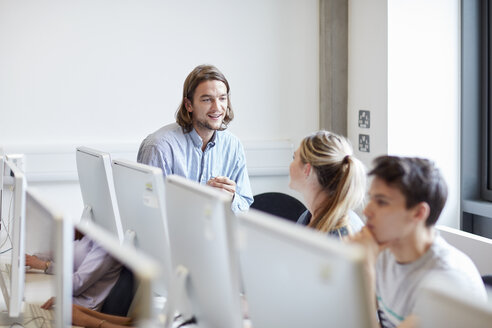 Männlicher Dozent im Gespräch mit einem Studenten im Computerraum einer Hochschule - CUF22196