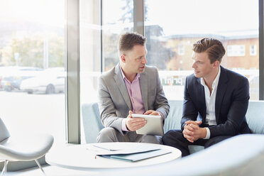 Two businessmen using digital table at office meeting - CUF22238