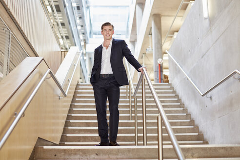 Porträt eines jungen Geschäftsmannes, der auf einer Bürotreppe steht - CUF22245