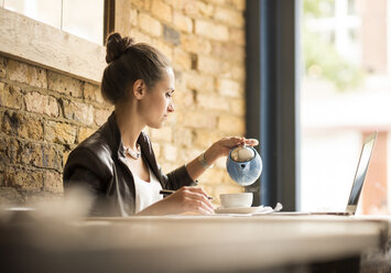 Junge Geschäftsfrau schenkt Tee in einem Café ein - CUF22253