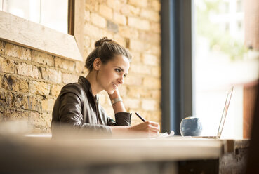 Young businesswoman making notes in cafe - CUF22254