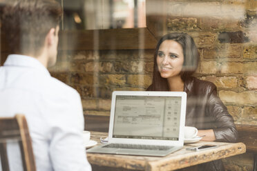 Young businessman and woman working with laptop and talking in cafe - CUF22256