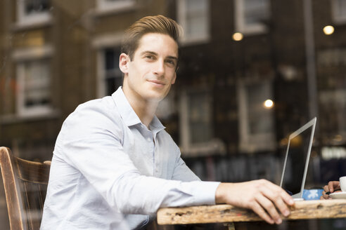 Fensteransicht eines jungen Geschäftsmannes mit Laptop in einem Café - CUF22262