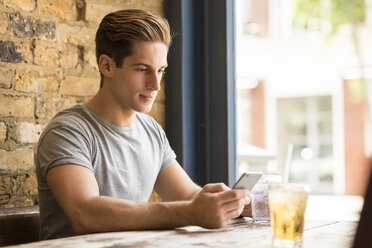 Young man reading smartphone text in bar - CUF22263