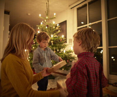 Mutter und Söhne sitzen an Weihnachten zu Hause und tauschen Geschenke aus - CUF22298