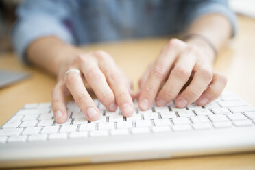 Close up of male designer typing on computer keyboard in printing press studio - CUF22347