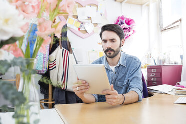 Junger männlicher Designer beim Lesen eines digitalen Tablets im Druckmaschinenstudio - CUF22348