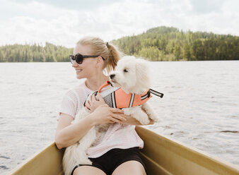 Frau hält einen Coton de Tulear-Hund in einem Boot, Orivesi, Finnland - CUF22365