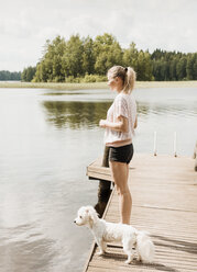 Frau mit Coton de tulear-Hund am Seeufer, Orivesi, Finnland - CUF22369