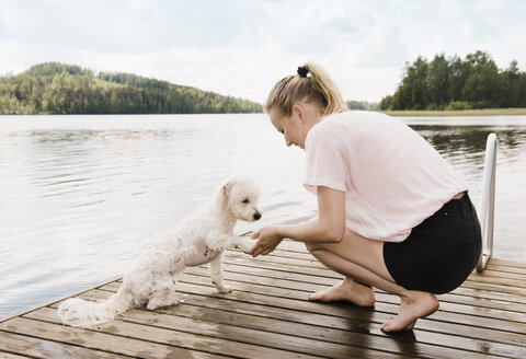 Frau hält die Pfote eines Coton de Tulear-Hundes nach dem Schwimmen, Orivesi, Finnland - CUF22372