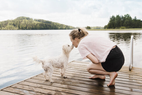 Woman kissing coton de tulear dog on pier, Orivesi, Finland - CUF22373