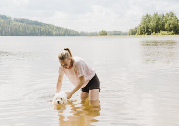 Frau trainiert Coton de Tulear-Hund im See zu schwimmen, Orivesi, Finnland - CUF22375