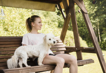 Frau auf Schaukelstuhl sitzend mit Coton de Tulear Hund, Orivesi, Finnland - CUF22376