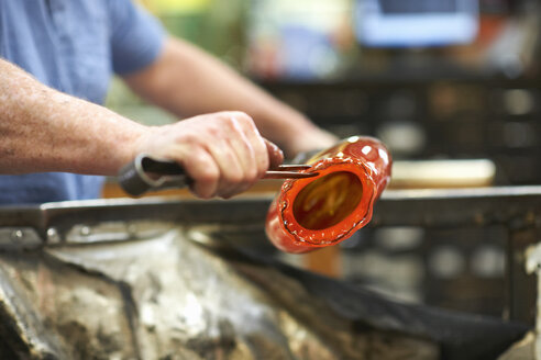 Glasbläser in der Werkstatt, der geschmolzenes Glas mit Handwerkzeugen formt - CUF22439