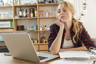 Woman with laptop looking at paperwork - CUF22474