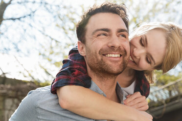 Man giving woman piggyback smiling - CUF22480