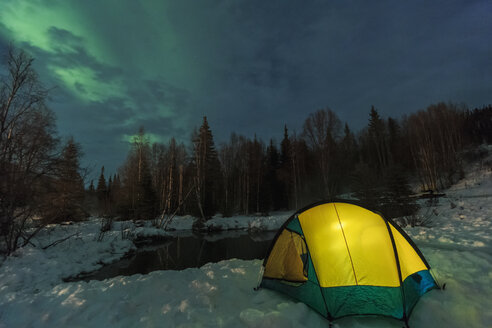 Aurora borealis, Nordlicht über dem mit einer Laterne beleuchteten Zelt, in der Nähe des Chena Resort, in der Nähe von Fairbanks, Alaska - ISF07925