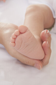 Mütter Hand hält Baby Jungen Fuß - ISF07930