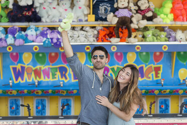 Couple in front of fairground shooting gallery holding teddy bear, Coney island, Brooklyn, New York, USA - ISF07938
