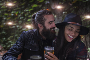 Young couple laughing in beer garden in evening, Brooklyn, New York, USA - ISF08054