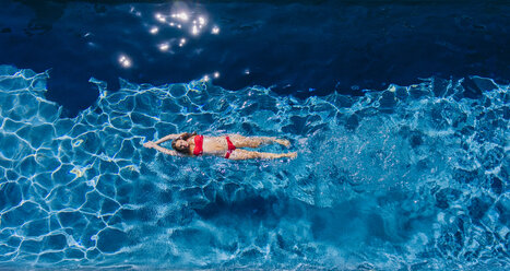 Overhead view of woman swimming on back in swimming pool - ISF08128