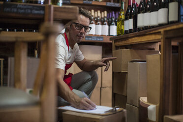 Mann im Weinladen, der Weinflaschen einlagert - ISF08149