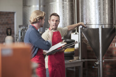 Colleagues in microbrewery discussing conical tank - ISF08153