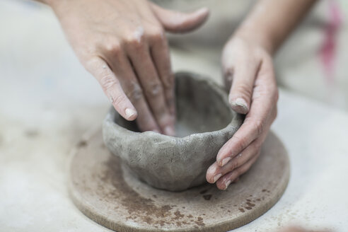 Hands of female potter shaping clay pot in workshop - ISF08157