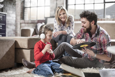 Parents showing vinyl record to son at home - ISF08179