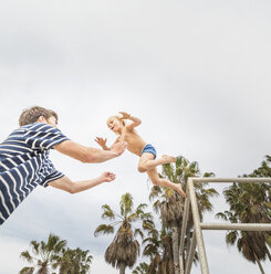 Junge springt in die Arme eines jungen Mannes am Venice Beach, Kalifornien, USA - ISF08183